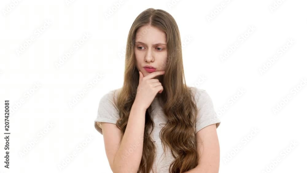 Portrait of adolescent woman with brown long hair being deep in thoughts doing pensive gesture while trying to choose best option, over white background. Concept of emotions Portrait of adolescent woman with brown long hair being deep in thoughts doing pensive gesture while trying to choose best option, over white background. Concept of emotions