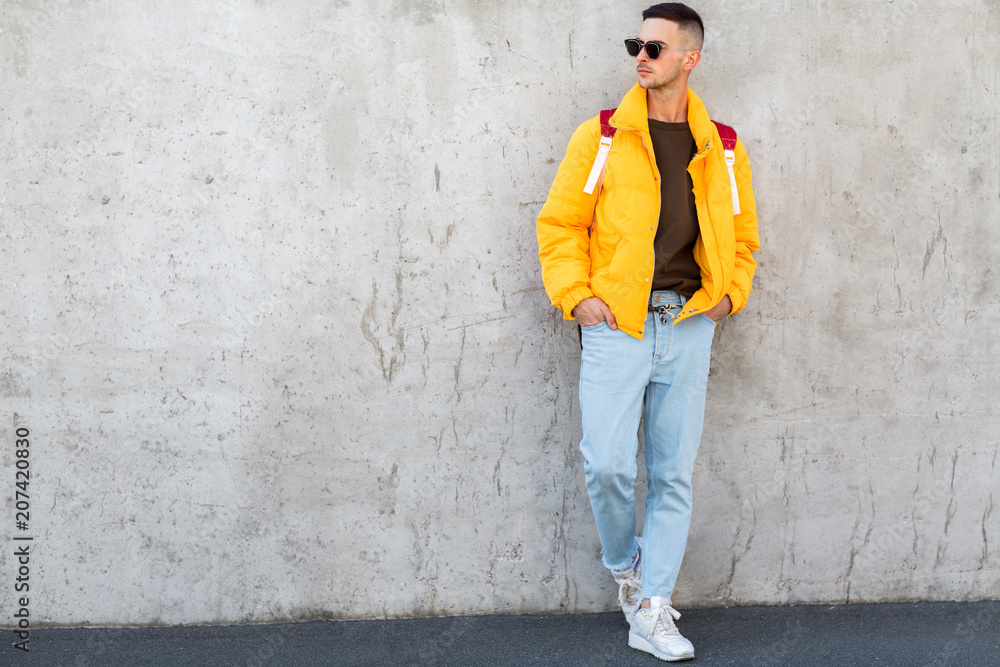 fashion guy standing near a concrete wall in yellow clothes
