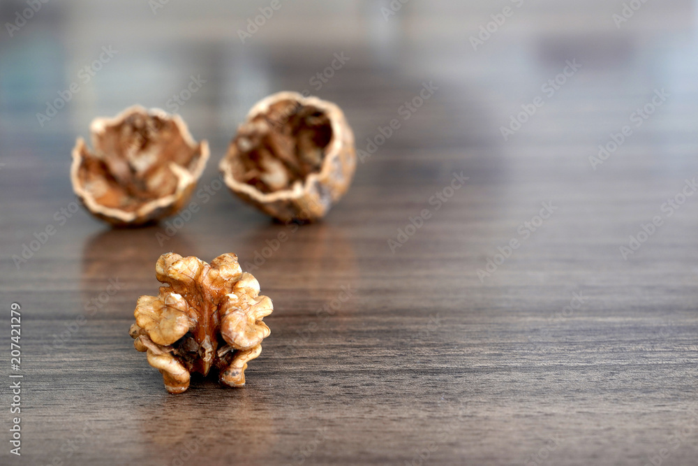 One kernel walnut with its nutshell on dark walnut table background