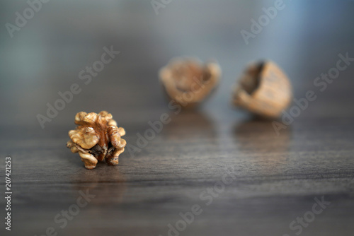 One kernel walnut with its nutshell on dark walnut table background
