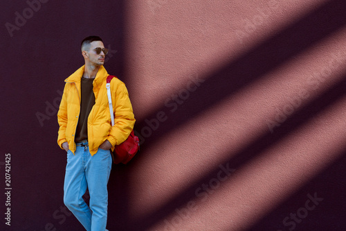 fashion guy standing near a broun wall in yellow clothes