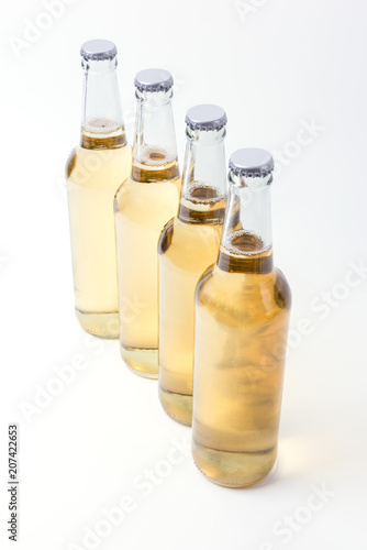 Four yellow bottles of beer on white background. 