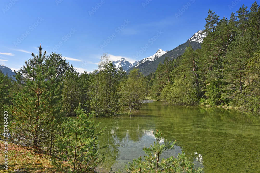 Pond in the Lech valley at a beautiful day in spring with snow-covered mountains and green forests. Tyrol, Austria Pond in the Lech valley at a beautiful day in spring with snow-covered mountains and green forests. Tyrol, Austria