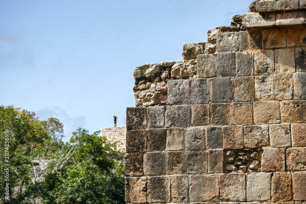 Part of the stone wall of the ancient Mayan pyramid. The man at the top of the pyramid. Mexico