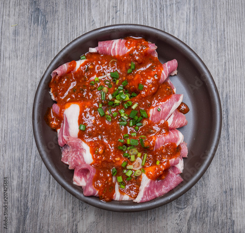 Картината върху платно Slice raw pork with marinate in ceramic plate on wood background