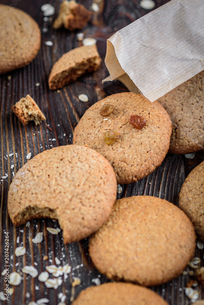 Homemade oatmeal cookies with raisins, cinnamon with milk on dark wooden background. Homemade oatmeal cookies with raisins, cinnamon with milk on dark wooden background.
