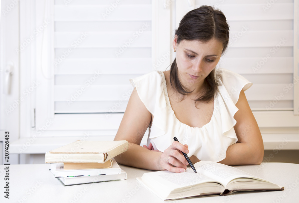 girl with textbooks prepares for examinations at the university. Young brunette teaches lessons. Woman at the session. A student at the hostel reads books. girl with textbooks prepares for examinations at the university. Young brunette teaches lessons. Woman at the session. A student at the hostel reads books.