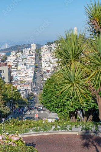 SAN FRANCISCO - AUGUST 7, 2017: Lombard Street and Russian Hill with San Francisco city skyline on a sunny summer day. The city attracts 20 million tourists annually