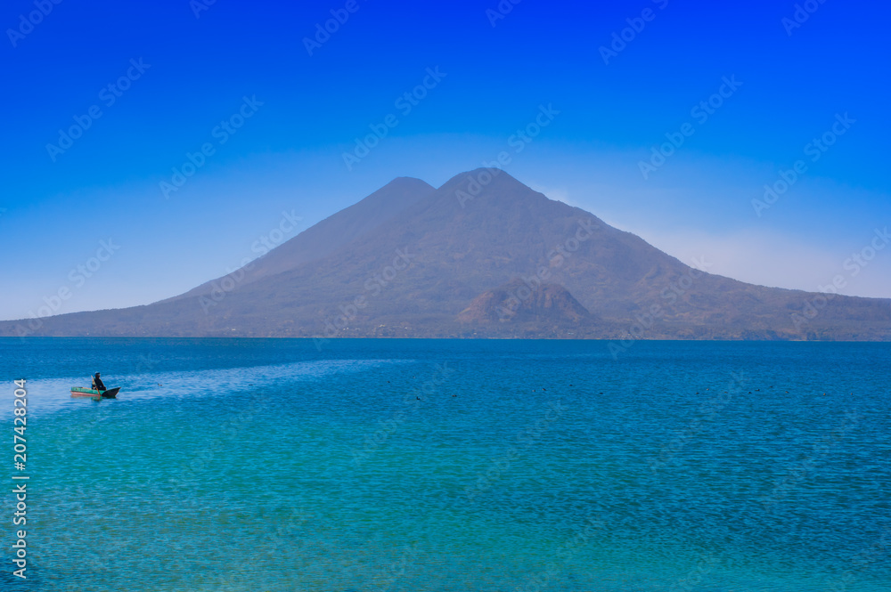 Beautiful outdoor view of small boats in Atitlan Lake is the deepest lake in all of Central America with a maximum depth of about 340 meters, with volcano in Background in Guatemala