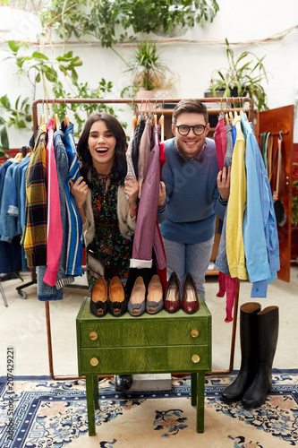 sale, shopping, fashion and people concept - happy couple having fun at vintage clothing store hanger