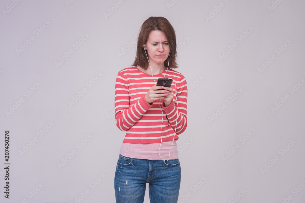 portrait of a beautiful brunette girl on a white background touching a smartphone portrait of a beautiful brunette girl on a white background touching a smartphone