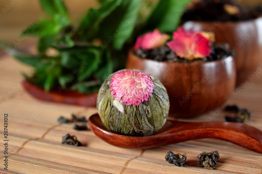Blossom tea ball and leaf tea with rose petals in wooden cups and spoon