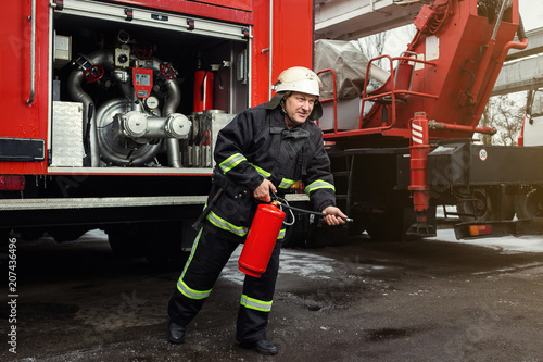 Fireman (firefighter) in action standing near a firetruck. Emergency safety. Protection, rescue from danger.