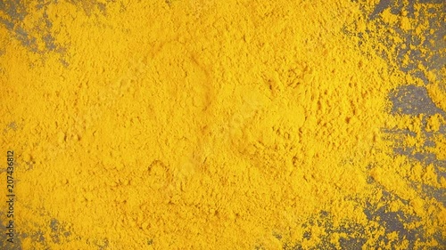 Slow motion turmeric powder dry spice drops on a gray background from under the camera