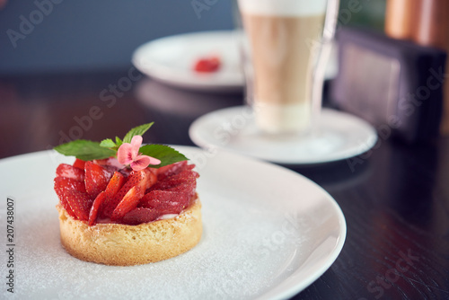 Strawberry tasty summer dessert with a green leaf of mint on a white plate