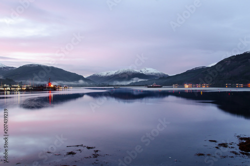 A view of Holy Loch, from Sandbank, near Dunoon in Argyll Scotland as the sun sets out of shot casting a beautiful blue, calm hue across the sky reflected in the waters of the loch. photo
