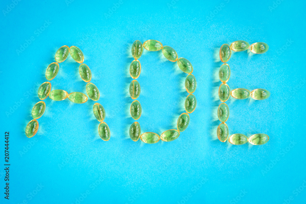 Yellow capsules forming shape to A, D and E alphabet on blue background Yellow capsules forming shape to A, D and E alphabet on blue background
