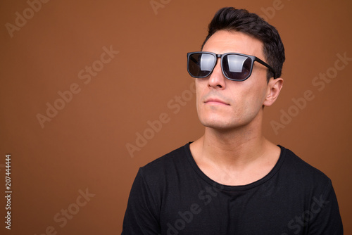 Young handsome Hispanic man against brown background © Ranta Images