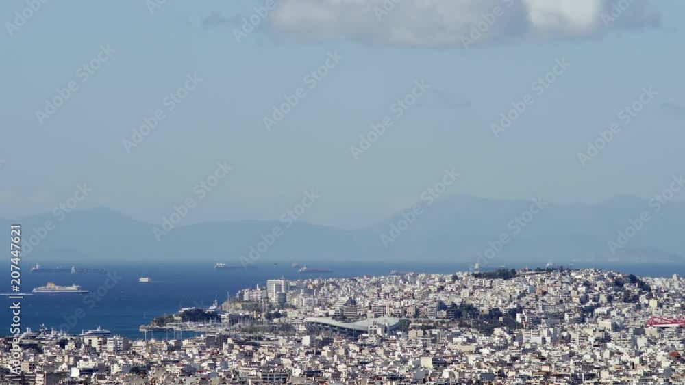 Wide Cityscape Shot Of Athens. The Peace And Friendship Stadium, The Piraeus Harbor With Ship Traffic In The Saronic Gulf, And The Peloponese Mountains Are Visible In The Background. Wide Cityscape Shot Of Athens. The Peace And Friendship Stadium, The Piraeus Harbor With Ship Traffic In The Saronic Gulf, And The Peloponese Mountains Are Visible In The Background.