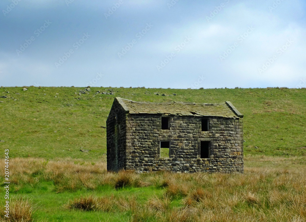 an old abandoned stone farmhouse in green pasture on high pennine moorland with bright blue sky an old abandoned stone farmhouse in green pasture on high pennine moorland with bright blue sky