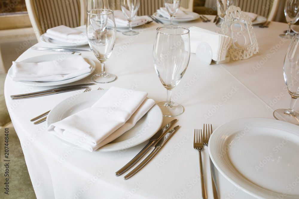 The round table is covered with a white tablecloth The round table is covered with a white tablecloth