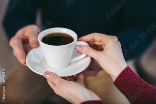 man giving woman cup of coffee