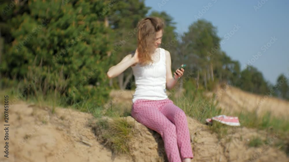Young woman using a smartphone in a forest. Beautiful girl typing on phone in the woods. Young woman using a smartphone in a forest. Beautiful girl typing on phone in the woods.