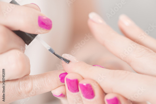 Manicure treatment at nail salon. Applying Nail Polish. Close up of women Fingers