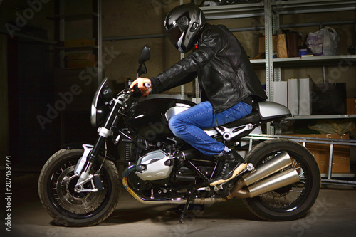 Stylish biker sits on his motorcycle in garage