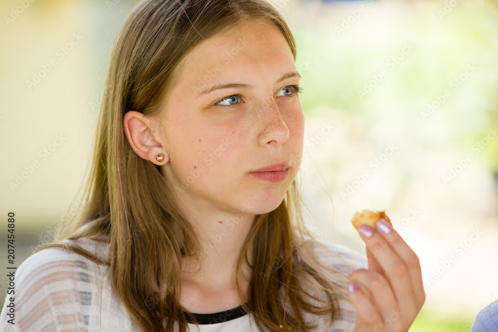 Beautiful young blonde girl eats small snack, outdoor