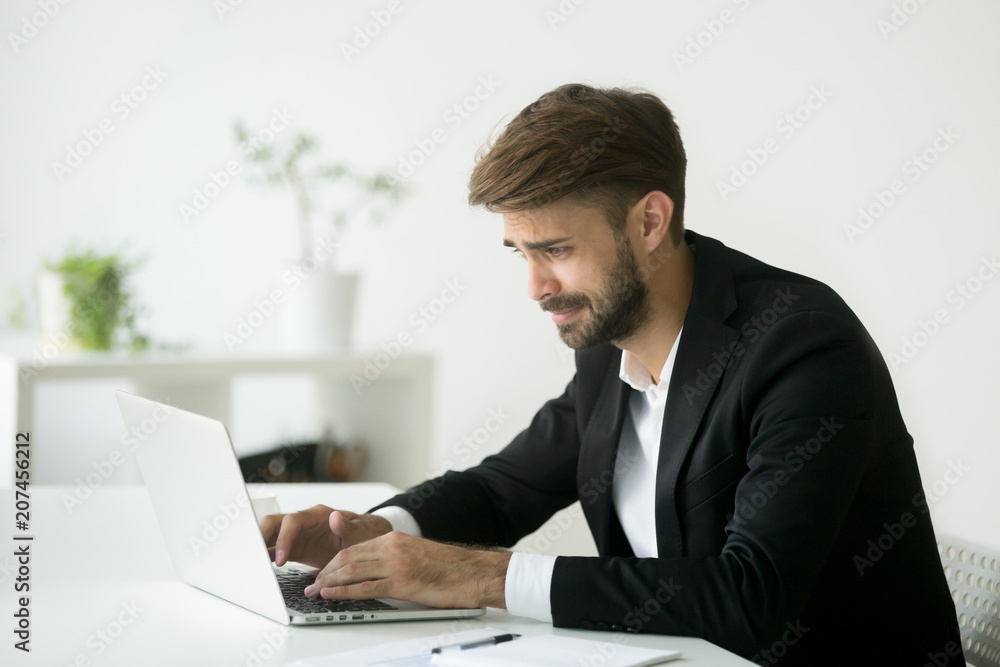 Stressed disappointed businessman worried about bad online news, reading about company financial crisis. Manager getting dismissal notice, receiving negative email