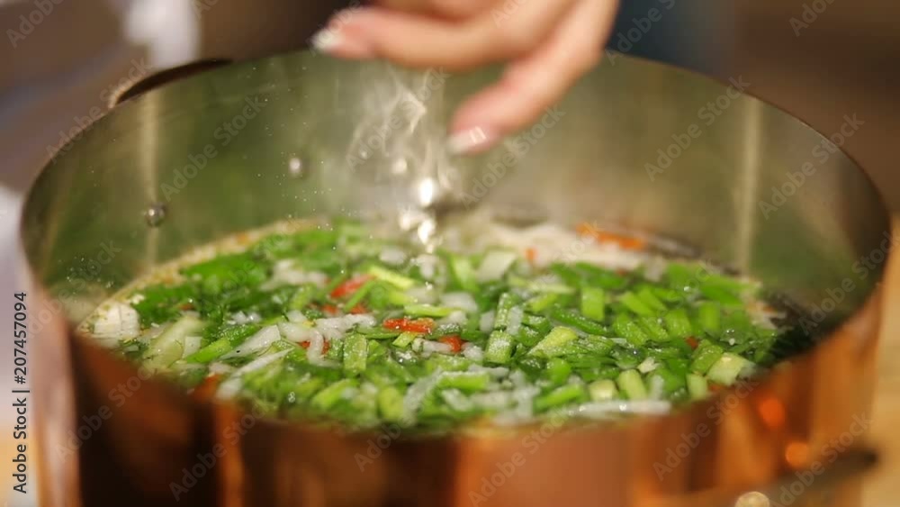 adding salt to the vegetable soup. soup from mussels, The process of cooking. close-up adding salt to the vegetable soup. soup from mussels, The process of cooking. close-up