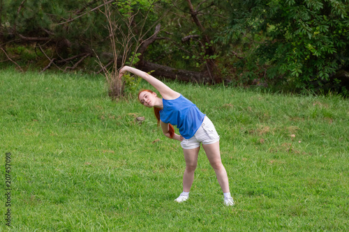 a girl is  doing sports exercises in the park © Gila78345
