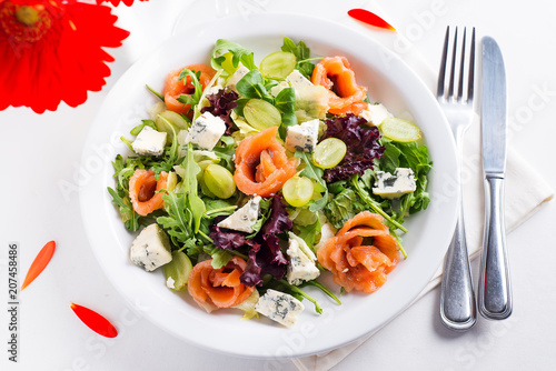 Delicious salad with salmon, grapes and cheese on a white background photo