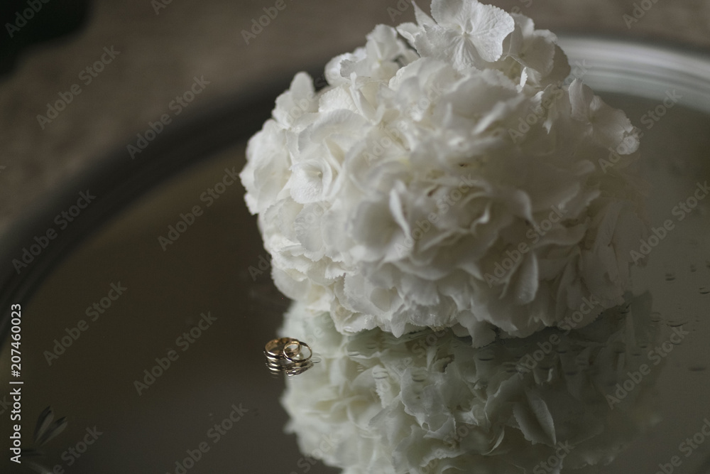 A bouquet of white hydrangeas and engagement rings lie on a glass table. Close-up horizontal photo A bouquet of white hydrangeas and engagement rings lie on a glass table. Close-up horizontal photo