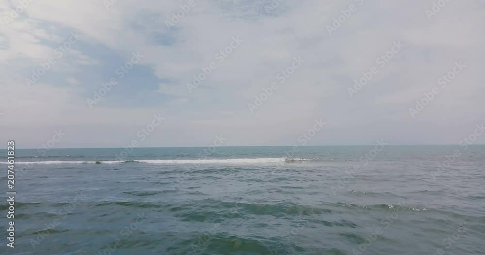 Drone moving up and forward above waves reaching shore to reveal amazing open ocean panorama and epic cloudy skyline. Drone moving up and forward above waves reaching shore to reveal amazing open ocean panorama and epic cloudy skyline.