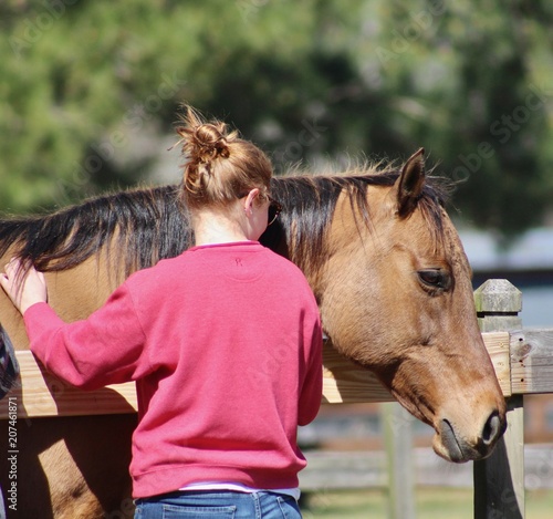 Redhead petting dun horse over fence