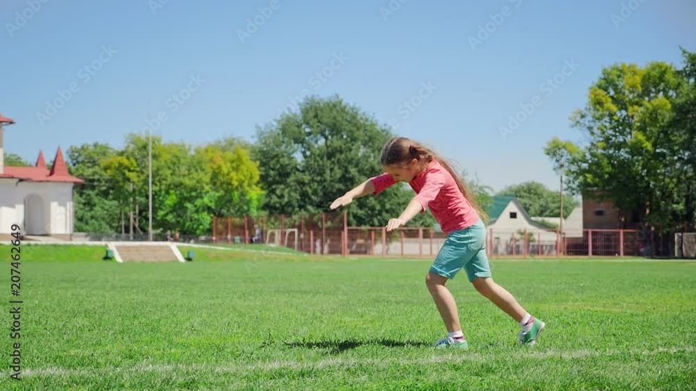 Beautiful girl makes a wheel. Girl of eight years old on the green grass makes a wheel at extreme slow-motion shot Beautiful girl makes a wheel. Girl of eight years old on the green grass makes a wheel at extreme slow-motion shot