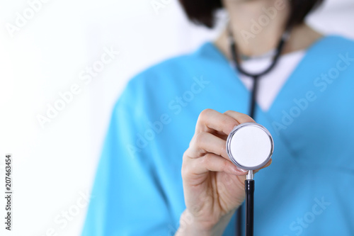 Female doctor holds stethoscope head closeup. Medical help and insurance in health care, best treatment and medicine concept