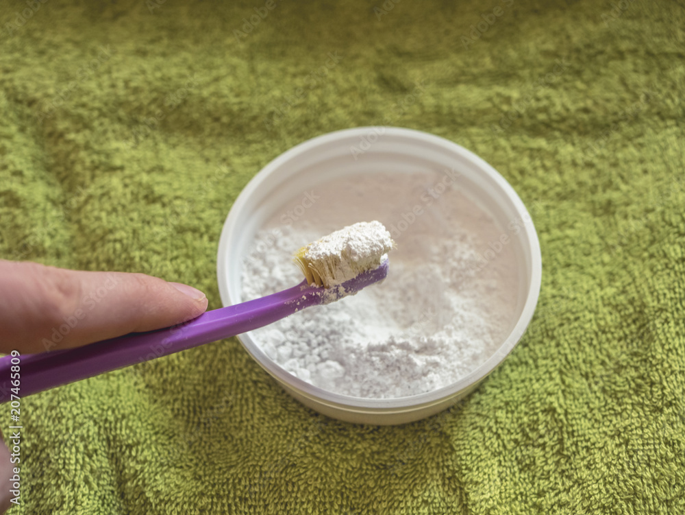 close up hand holding toothbrush over the cup with dentifrice, towel texture background close up hand holding toothbrush over the cup with dentifrice, towel texture background