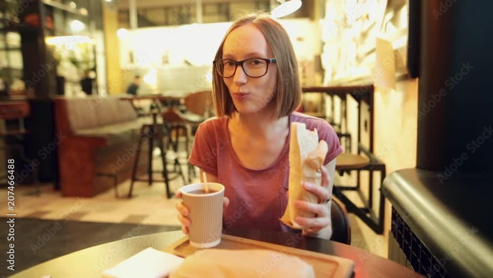 Hungry smiling woman is eating a delicious chicken shawarma or doner. Hungry smiling woman is eating a delicious chicken shawarma or doner.