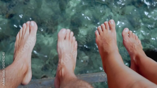 Couple sitting on the pier and swinging feet over the rippled ocean water photo