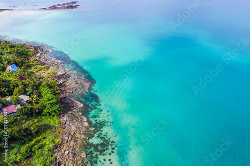 Rocky sea beach turquoise clear water with green forest.