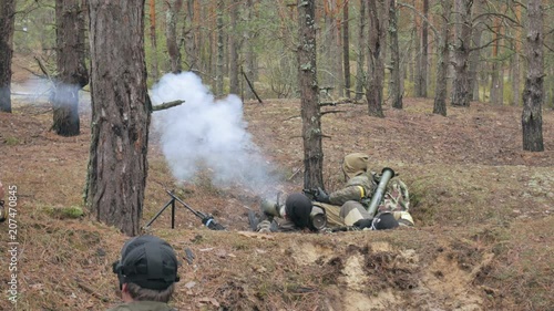 Soldiers in camouflage with combat weapons are being fired in the shelter of the forest, the military concept photo