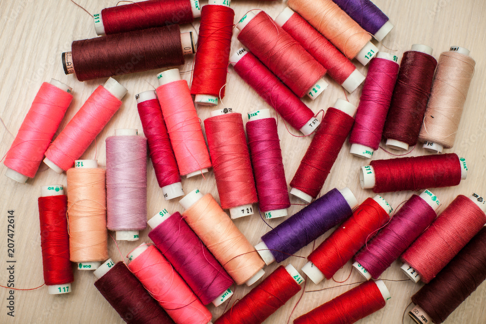 pink and red sewing threads on wood table. top view, selective focus pink and red sewing threads on wood table. top view, selective focus