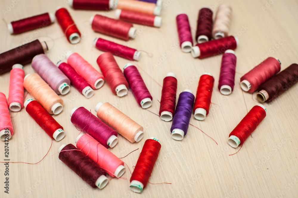 pink and red sewing threads on wood table. top view, selective focus pink and red sewing threads on wood table. top view, selective focus