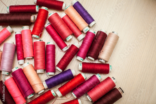 pink and red sewing threads on wood table. top view, selective focus