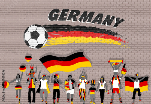 German football fans cheering with Germany flag colors in front of soccer ball graffiti