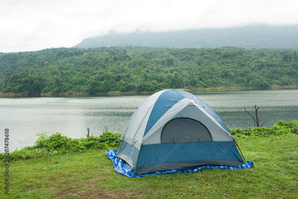 Tent on the grass, with backdrops are reservoirs, forests, mountains and fog, morning.