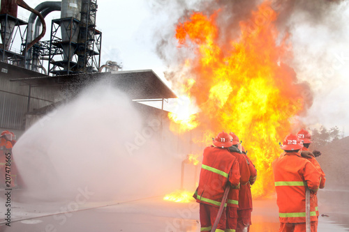Wallpaper Mural  fireman using water and extinguisher to fighting with fire flame in an emergency situation.All firemen wearing fire fighter suit for safety. Torontodigital.ca